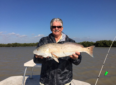 fisherman holding redfish in arroyo city